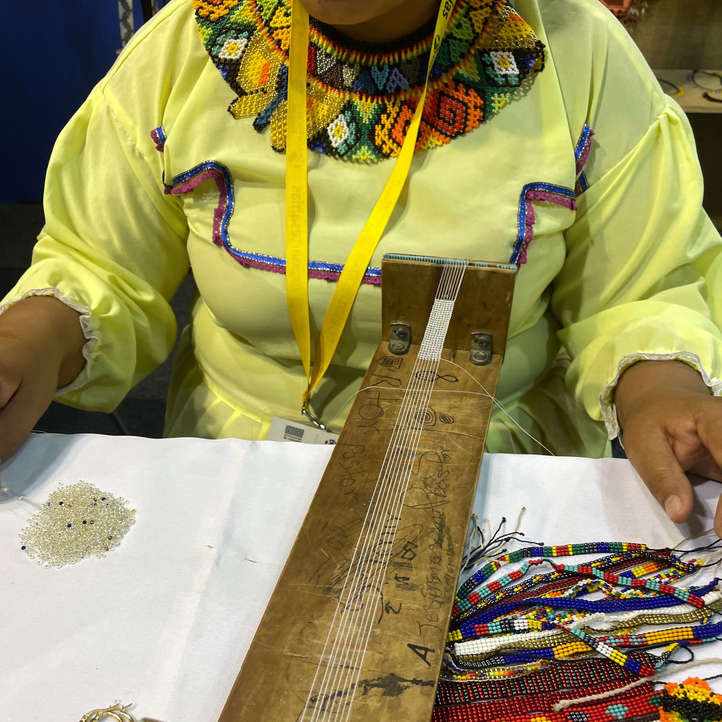 Artesana indígena Embera elaborando collar a mano en telar tradicional - Proceso artesanal colombiano